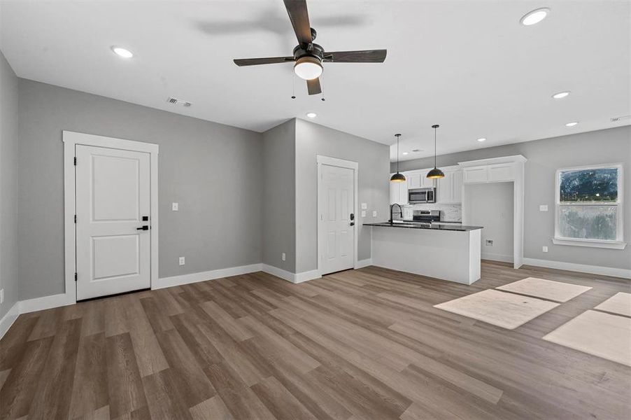 Unfurnished living room with ceiling fan, light hardwood / wood-style flooring, and sink