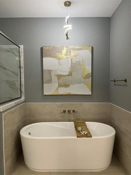 Full bath featuring tile walls, a freestanding bath, a wainscoted wall, and tile patterned floors Full bath featuring tile walls, a freestanding bath, a wainscoted wall, and tile patterned floors