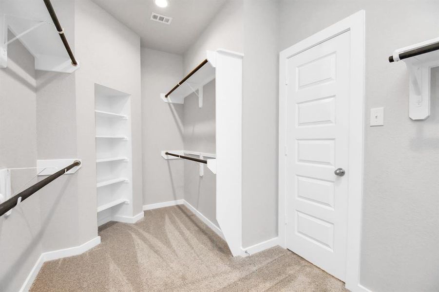 Discover luxury in this expansive walk-in closet, adorned with high ceilings and luxurious carpet. Sample photo of completed home with similar floor plan. Actual colors and selections may vary.