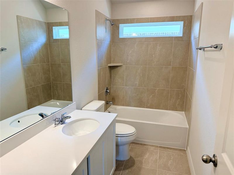 Bathroom featuring a single vanity with a white countertop and integrated sink, a full-width mirror, and a combination shower/tub with tile surround
