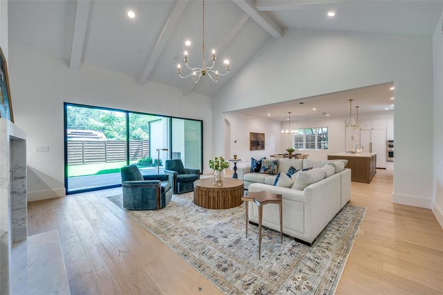 Living room featuring a chandelier, beam ceiling, light wood-type flooring, high vaulted ceiling, and recessed lighting