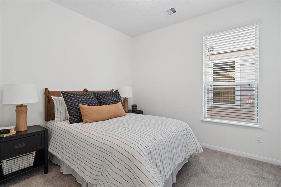 Secondary bedroom features plush carpet, high ceilings, ample closet space, and a large window with privacy blinds.