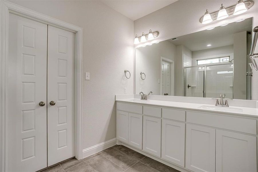 Full bathroom featuring a stall shower, double vanity, and light tile patterned floors Full bathroom featuring a stall shower, double vanity, and light tile patterned floors