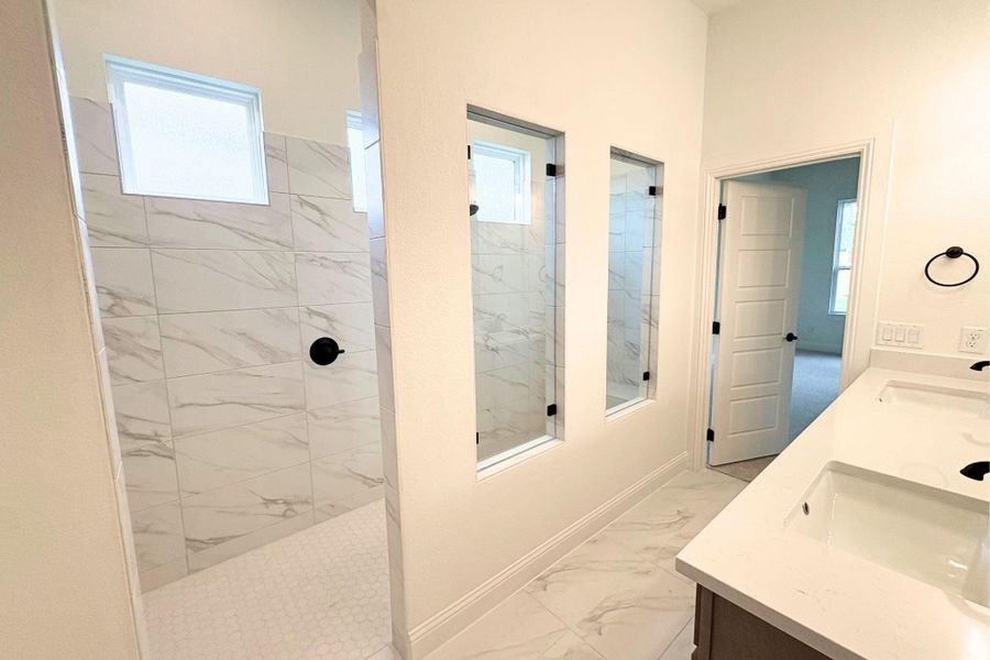 Elegant tile flooring complements a modern walk-in shower and stone-counter vanity in this bathroom. Elegant tile flooring complements a modern walk-in shower and stone-counter vanity in this bathroom.