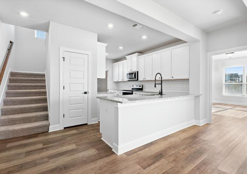 Designer kitchen situated next to the carpeted main staircase overlooking the main living area.