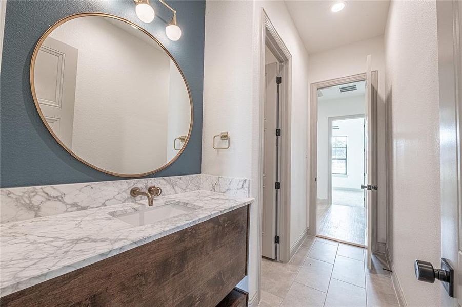 Bathroom with vanity, light tile patterned floors, and a textured wall Bathroom with vanity, light tile patterned floors, and a textured wall