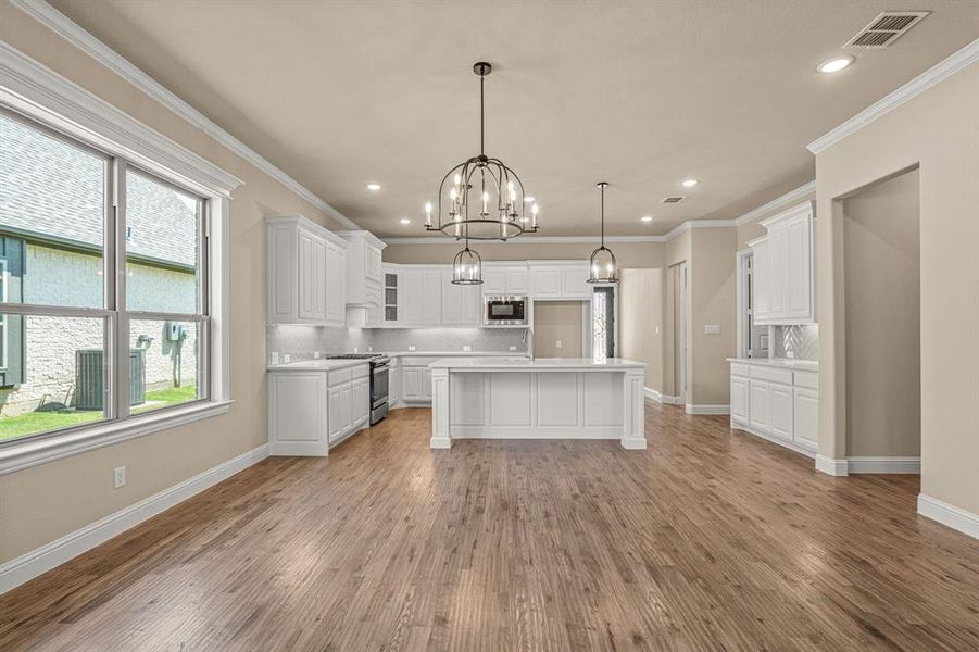 Kitchen featuring decorative backsplash, white cabinets, light hardwood / wood-style floors, appliances with stainless steel finishes, and a center island