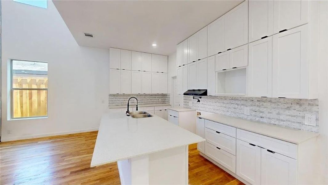 Modern kitchen featuring a large center island with a sink and gooseneck faucet
