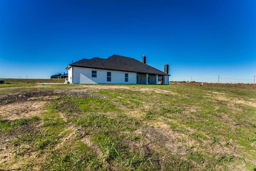 Back of house featuring a rural view and a yard