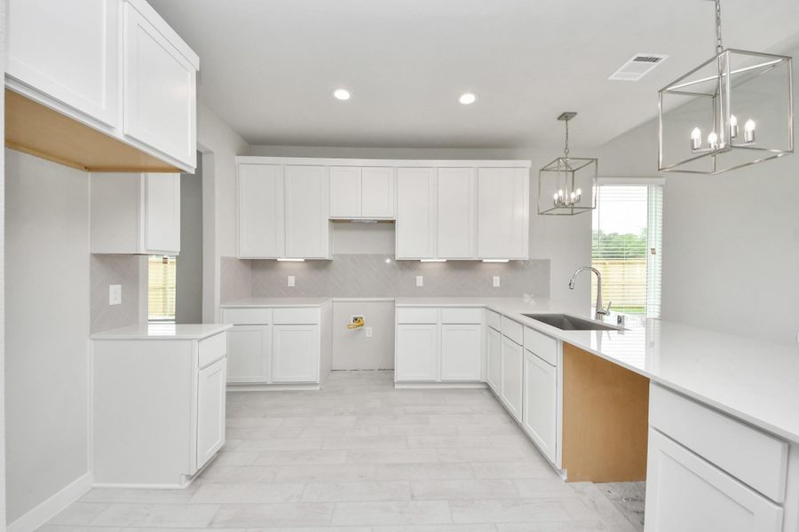 The kitchen is a culinary haven, featuring granite countertops, a tile backsplash, stainless steel appliances, 42” upper cabinets, and undercabinet lighting. Sample photo of completed home with similar floor plan. Actual colors and selections may vary. The kitchen is a culinary haven, featuring granite countertops, a tile backsplash, stainless steel appliances, 42” upper cabinets, and undercabinet lighting. Sample photo of completed home with similar floor plan. Actual colors and selections may vary.