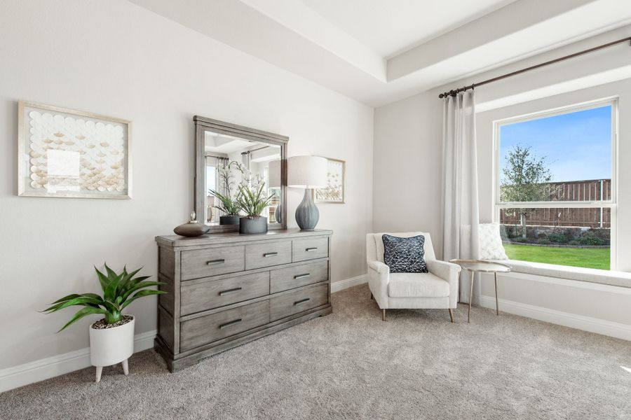 Bedroom with gray wood dresser, white accent chair, and large window with backyard view Bedroom with gray wood dresser, white accent chair, and large window with backyard view