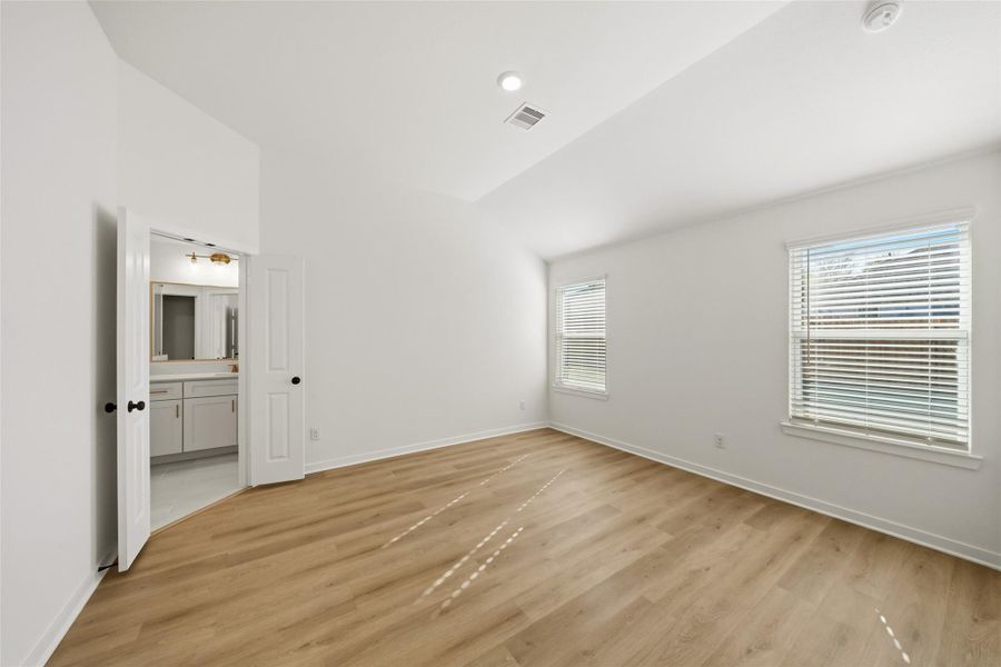 A view of the primary suite with ensuite bath beyond. This rooms is perfectly suited for a king-sized bed and two nightstands.