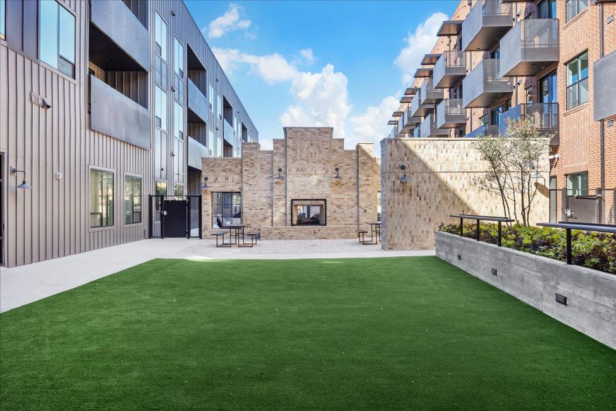 An inviting courtyard with an outdoor fireplace and a vibrant green lawn for community gatherings. An inviting courtyard with an outdoor fireplace and a vibrant green lawn for community gatherings.