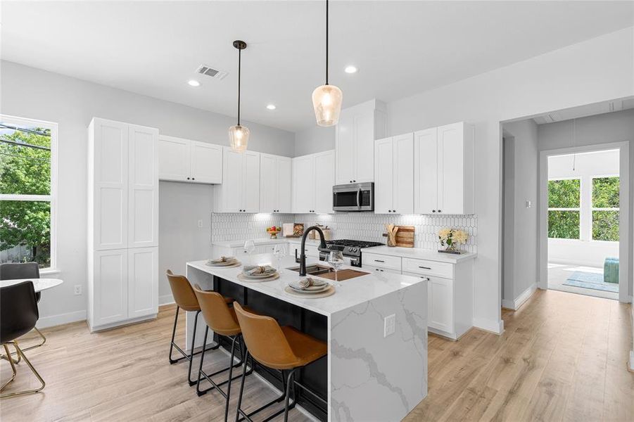 The kitchen, accented by a three-seater waterfall island, blends soft-close cabinets and polished black finishes harmoniously with elegant pendant lighting.