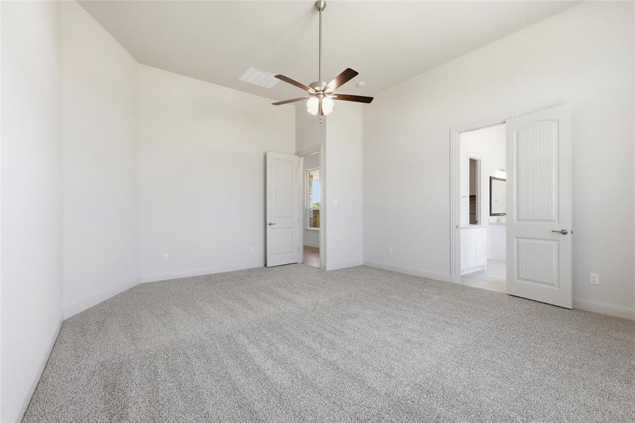 Unfurnished bedroom featuring light colored carpet, a high ceiling, and a ceiling fan