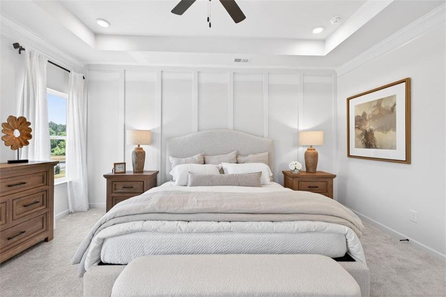 Recessed lighting and a ceiling fan illuminate this space featuring a tray ceiling