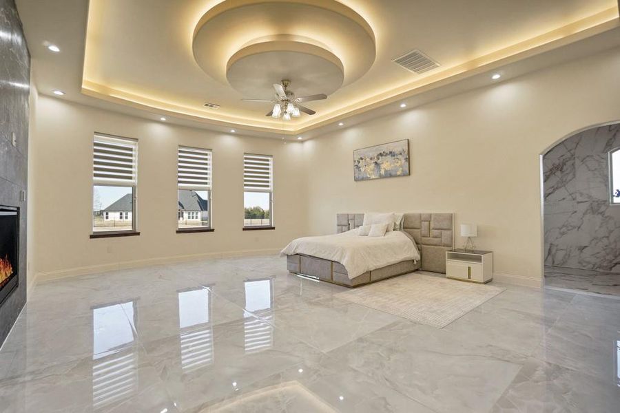 Bedroom with a large fireplace and a tray ceiling