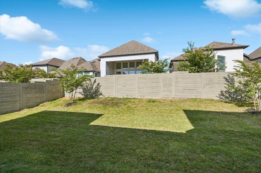 Expansive backyard featuring a lush lawn, mature trees, and a horizontal slatted privacy fence Expansive backyard featuring a lush lawn, mature trees, and a horizontal slatted privacy fence