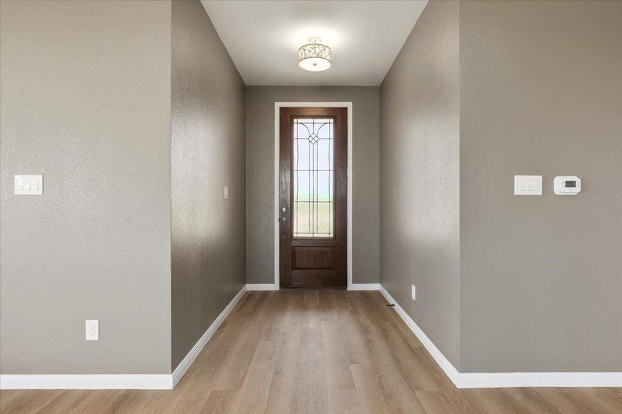 A welcoming entryway with warm wood-tone flooring and a classic paneled door with decorative glass. A welcoming entryway with warm wood-tone flooring and a classic paneled door with decorative glass.