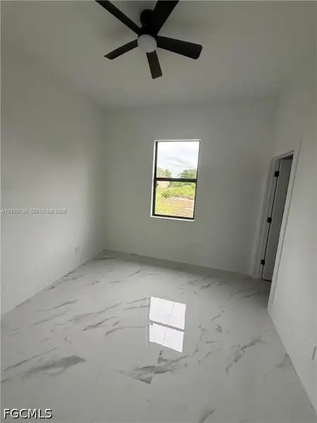Interior room featuring large-format tile flooring with a neutral veined pattern, matte black ceiling fan, and a single-pane window
