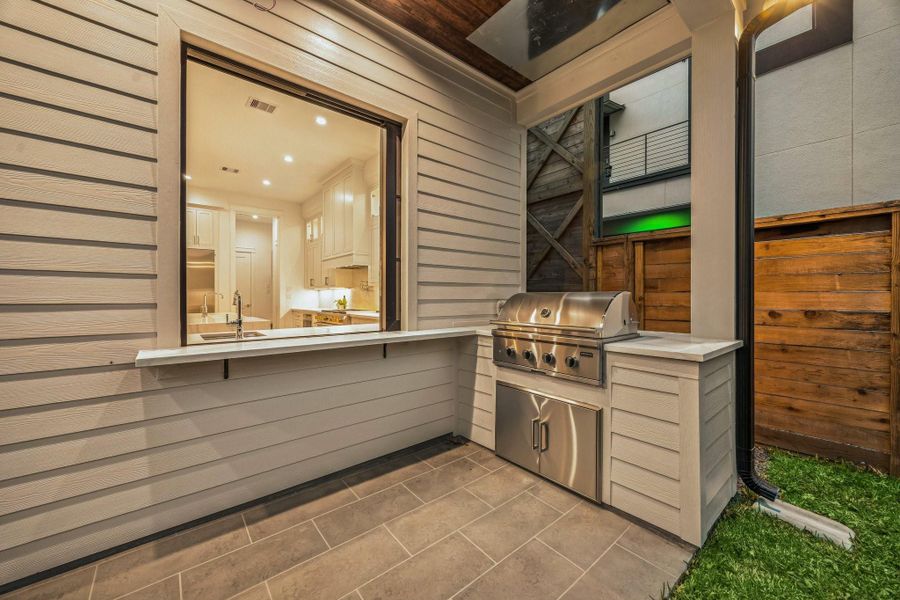 Outdoor Grill with a Built-In Bar Area. There is a Sliding Glass Window to pass drinks and food back and forth to the outside Bar/Grill Area. There is also a Coyote S-Series 36" Rapid Sear Built-In Stainless Steel Gas Grill and Coyote 36" Double Access Stainless Steel Doors.