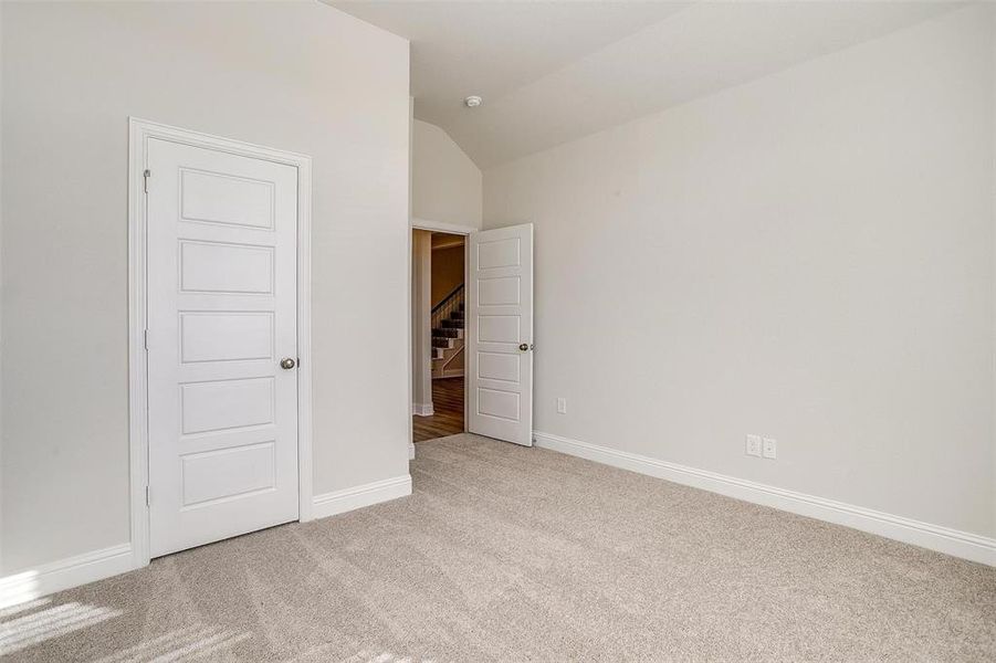 Unfurnished bedroom with light colored carpet and lofted ceiling