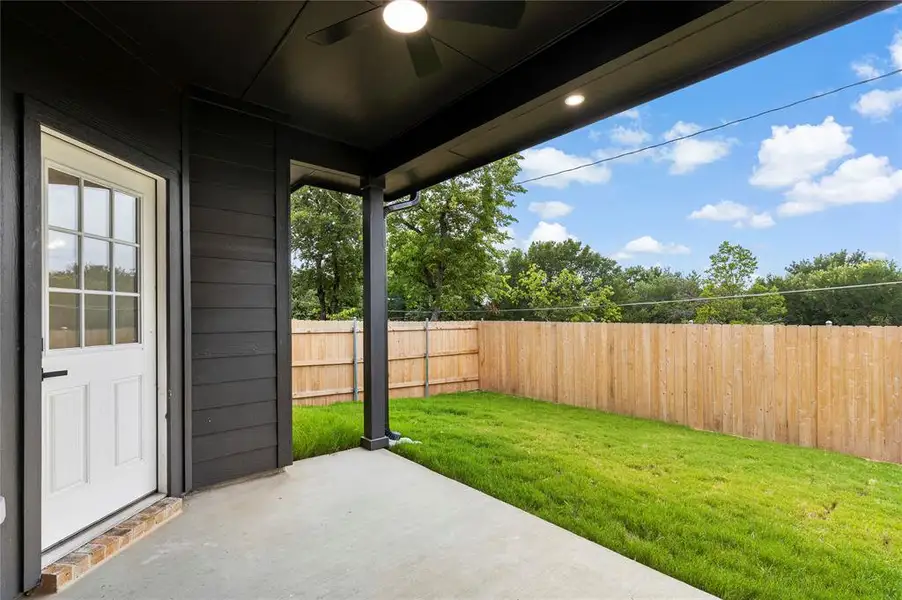 Modern siding exterior with multiple large windows, a covered patio, and a spacious green lawn