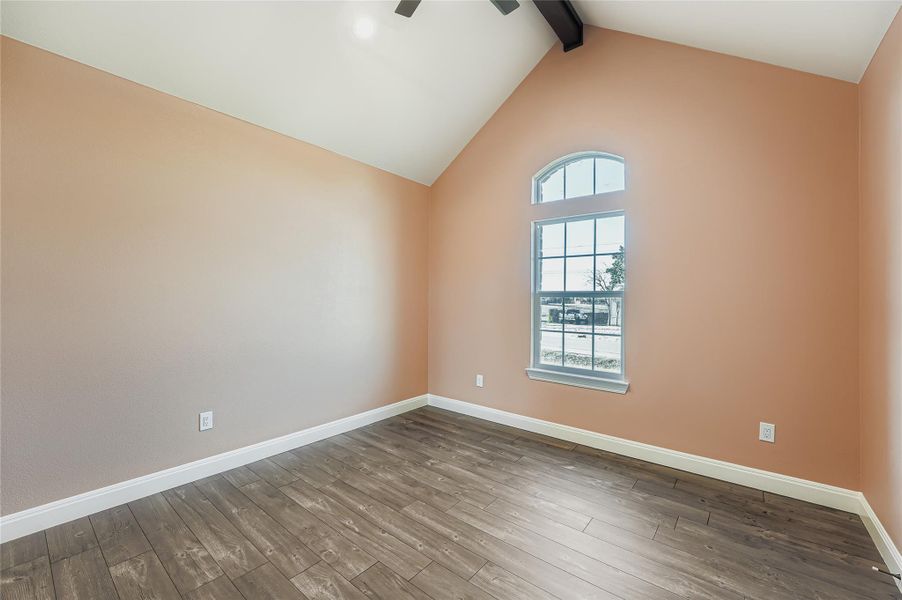 Spare room featuring wood-type flooring, beamed ceiling, ceiling fan, and high vaulted ceiling
