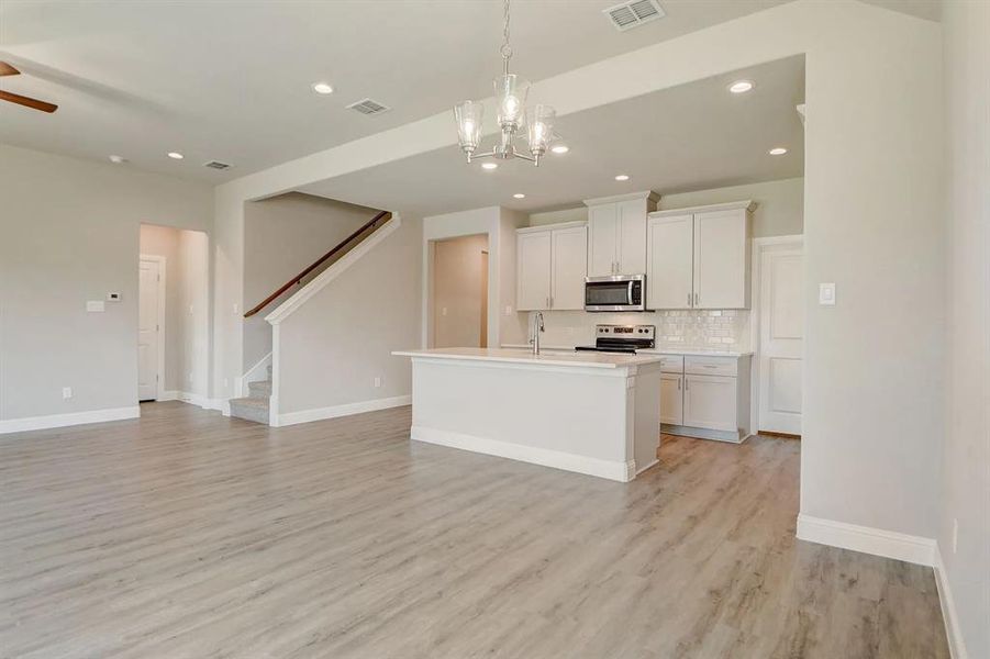 Kitchen with appliances with stainless steel finishes, decorative backsplash, open floor plan, light wood-type flooring, and recessed lighting