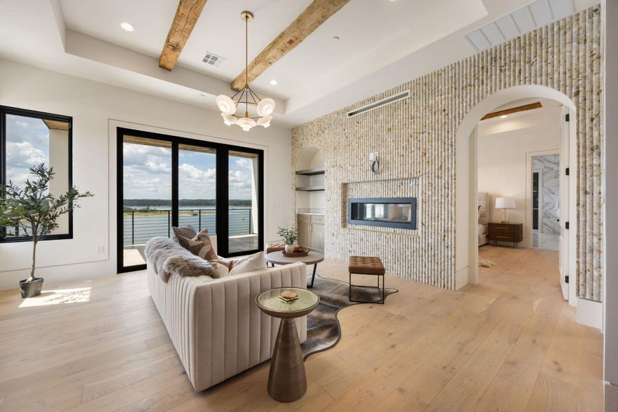 Elegant living space showcasing a water view, warm wooden beams, and a modern fireplace. Elegant living space showcasing a water view, warm wooden beams, and a modern fireplace.