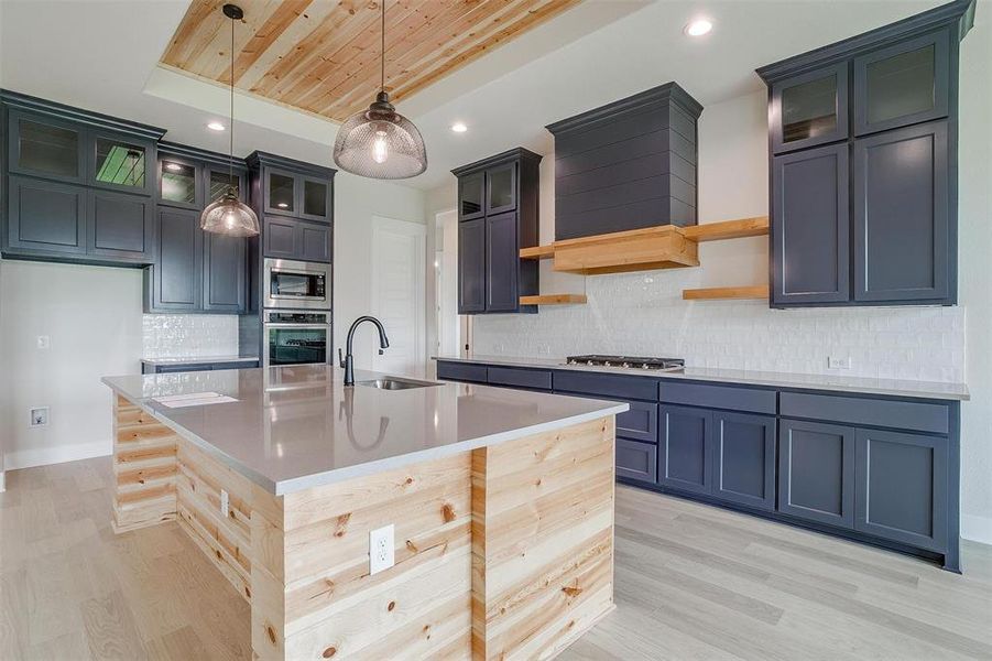 Kitchen with stainless steel appliances, a center island with sink, sink, and light wood-type flooring