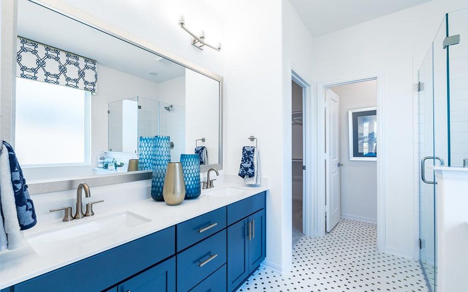 Bathroom featuring a shower stall, a spacious closet, double vanity, tile patterned floors, and baseboards Bathroom featuring a shower stall, a spacious closet, double vanity, tile patterned floors, and baseboards