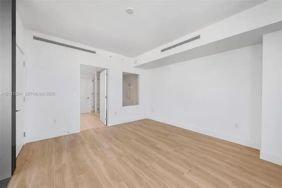 Minimalist interior featuring wood-finish flooring, recessed ceiling lighting, and a square wall niche Minimalist interior featuring wood-finish flooring, recessed ceiling lighting, and a square wall niche