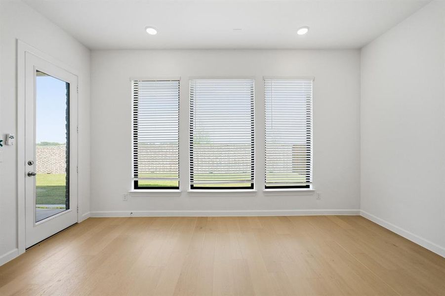 Room featuring light wood-finish flooring, recessed lighting, and three large windows fitted with horizontal blinds Room featuring light wood-finish flooring, recessed lighting, and three large windows fitted with horizontal blinds