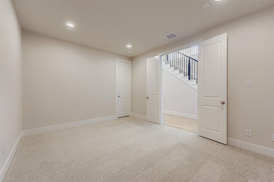 Basement featuring light carpet, recessed lighting, and stairway