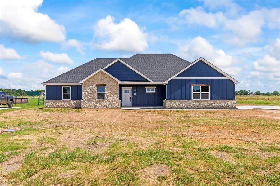View of front facade with stone siding, board and batten siding, and a shingled roof