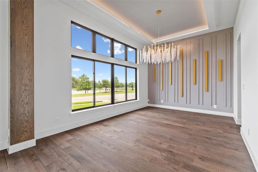 Unfurnished room featuring dark wood-type flooring, a chandelier, and a raised ceiling