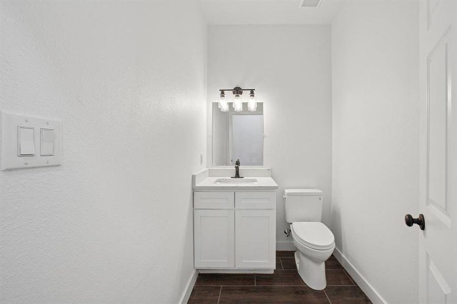 Half bathroom with vanity and wood finish floors