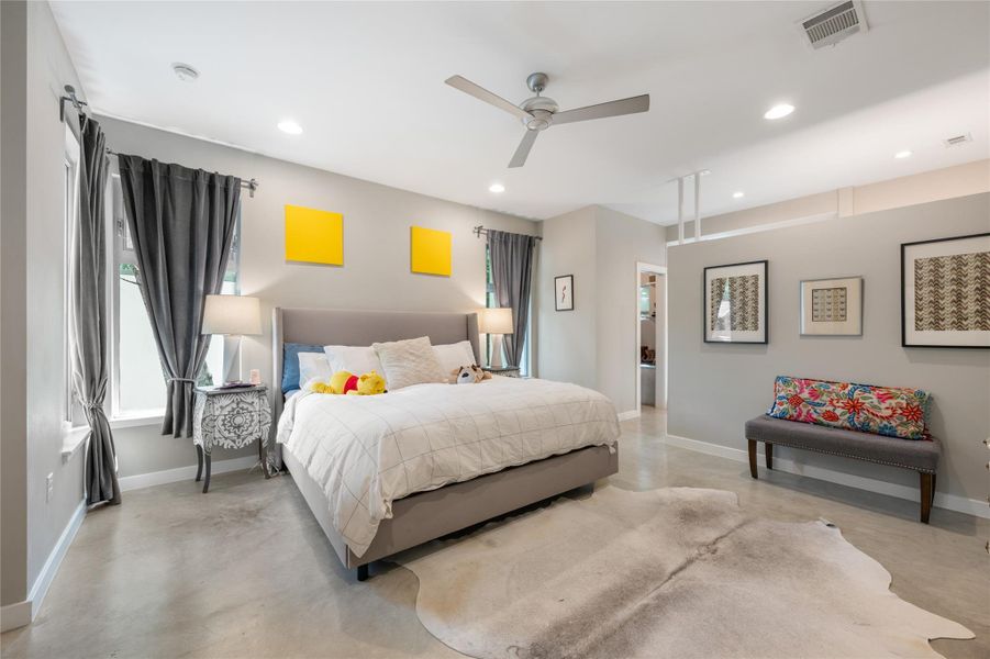 A tranquil primary bedroom features an open layout, a contemporary ceiling fan, and concrete flooring. A tranquil primary bedroom features an open layout, a contemporary ceiling fan, and concrete flooring.
