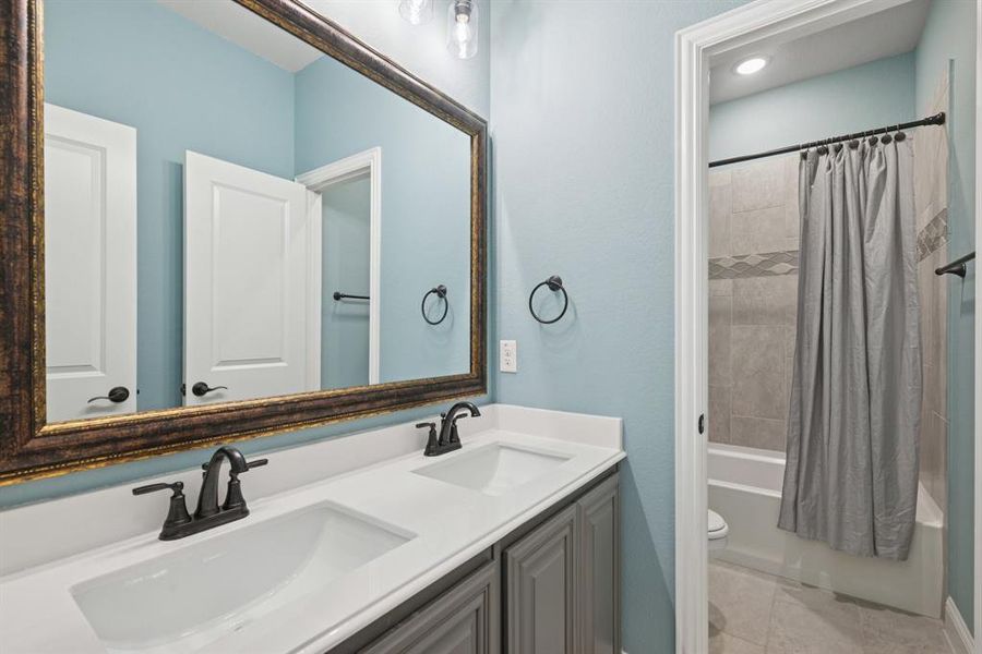 Bathroom with shower / bathtub combination with curtain, double vanity, and tile patterned floors Bathroom with shower / bathtub combination with curtain, double vanity, and tile patterned floors