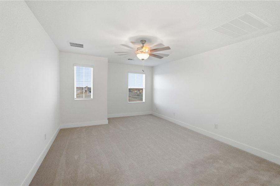 Empty room featuring light colored carpet and a ceiling fan