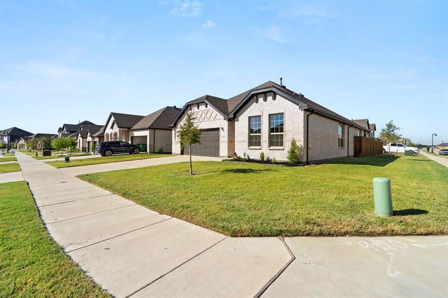 View of front of home featuring brick siding, concrete driveway, a front yard, and a residential view View of front of home featuring brick siding, concrete driveway, a front yard, and a residential view