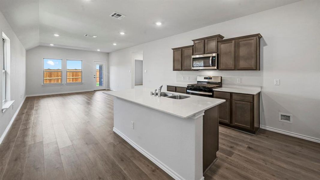 Open-concept living space featuring wood-finish flooring, recessed lighting, and a vaulted ceiling