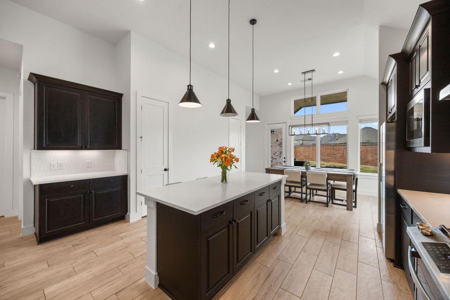 Extensive upper and lower cabinetry, under-cabinet lighting, and additional counter space offer practical storage and organization.