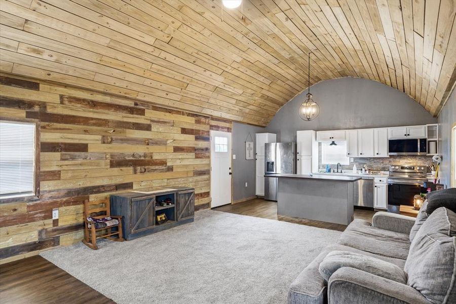 Living area featuring dark wood-style flooring, a vaulted wood ceiling, and wood walls