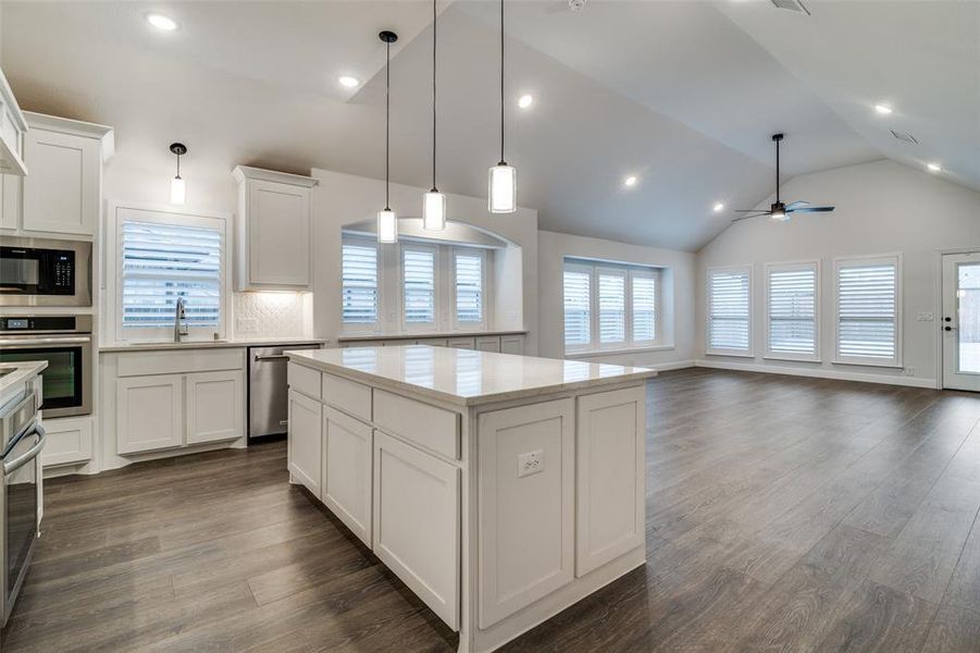 Kitchen featuring a Designer Upgrade, backsplash, white cabinets, ceiling fan, a kitchen island, and stainless steel appliances. TWO Ovens!