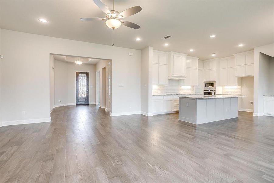 Kitchen featuring ceiling fan, light wood-type flooring, and an island with sink