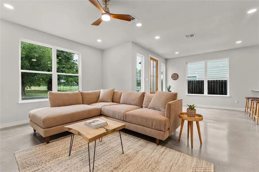 Living room with concrete flooring, ceiling fan, and recessed lighting Living room with concrete flooring, ceiling fan, and recessed lighting