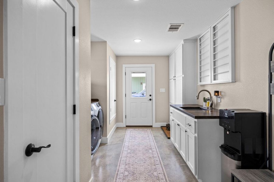 Laundry room with finished concrete floors, washer / clothes dryer, and a textured wall