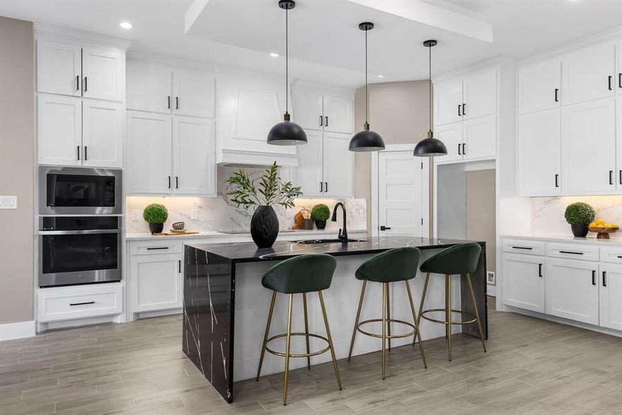 Kitchen featuring white cabinets, pendant lighting, built in microwave, and stainless steel oven